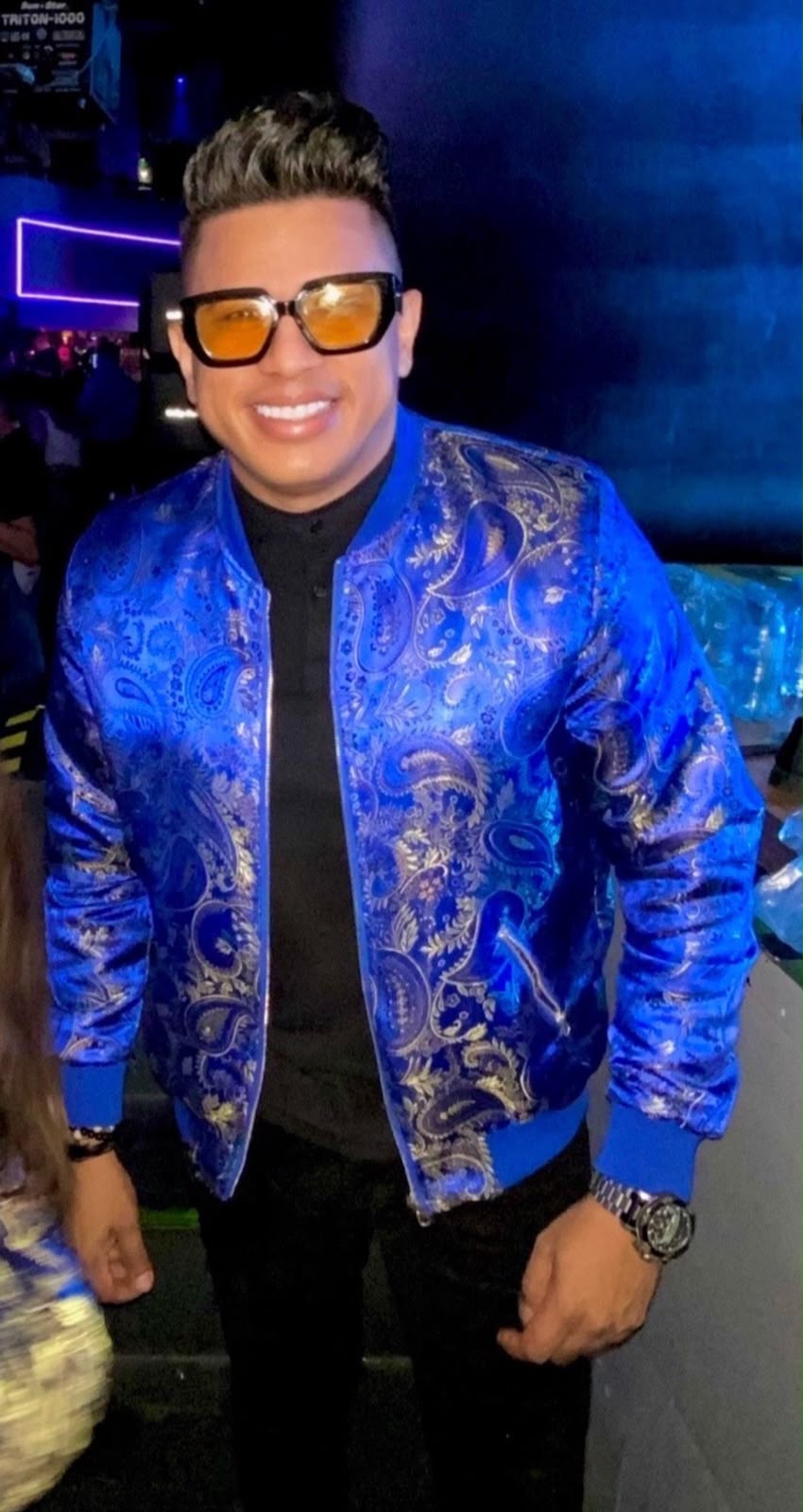 Emi Santiago con atuendo azul y gafas amarillas en evento